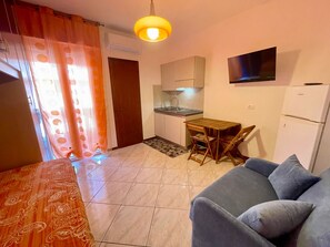 A compact living space with a kitchenette, a dining area, and a seating area. - Practical studio with balcony by the beach (Porto Santa Margherita)