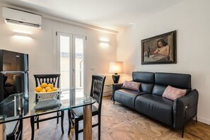 Ein modernes Wohnzimmer mit einem Glastisch, einem schwarzen Ledersofa und einem Gemälde an der Wand.