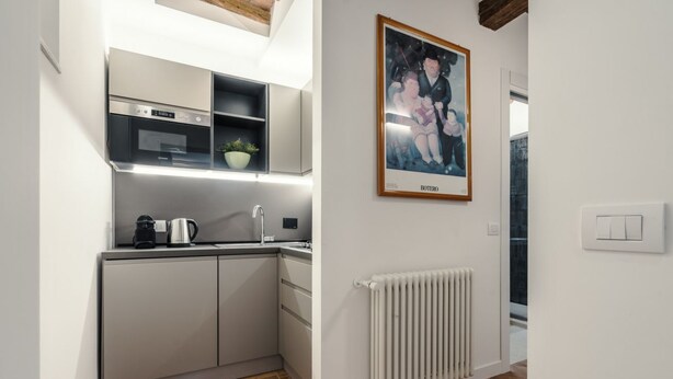 A modern kitchen with built-in appliances, a radiator, and a framed artwork on the wall. - CS Spanish Steps Boutique B Apartment (Roma)