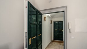A hallway with a closed door, a light switch, and a telephone on the wall. - CS Spanish Steps Boutique B Apartment (Roma)