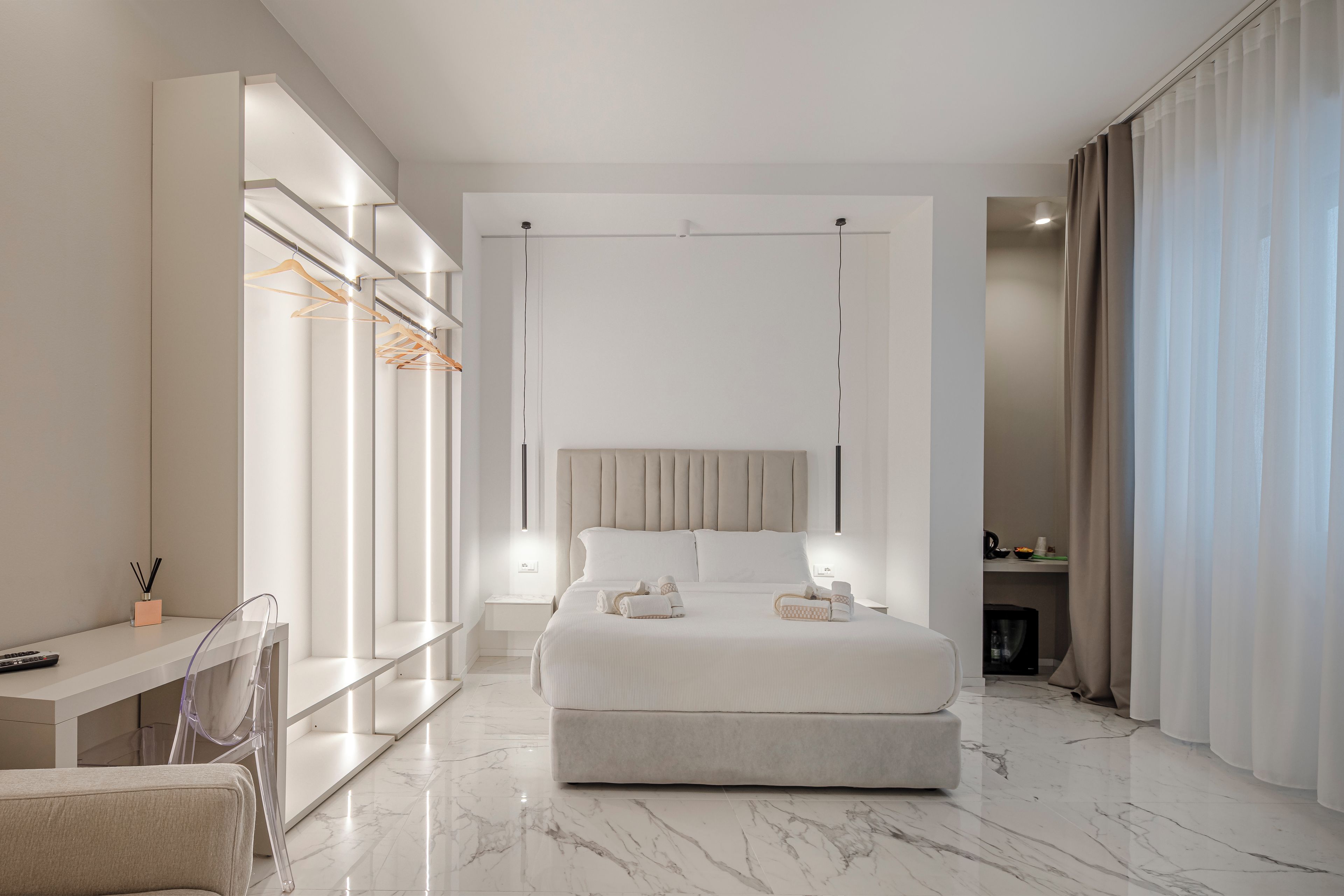 A modern bedroom with a large bed, bedside tables, a desk, and a chair.