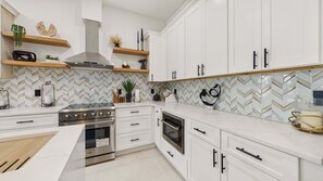 A modern kitchen with white cabinetry, a stainless steel range, and a herringbone tile backsplash. - Sunset Oasis 21403-Private Pool-Sleeps 14 (Panama City Beach)