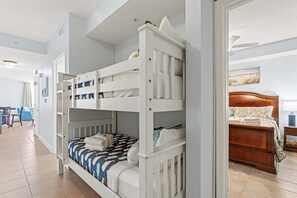 Ein Zimmer mit Etagenbetten, einem Holzbett, einem Schreibtisch und einem Stuhl.
