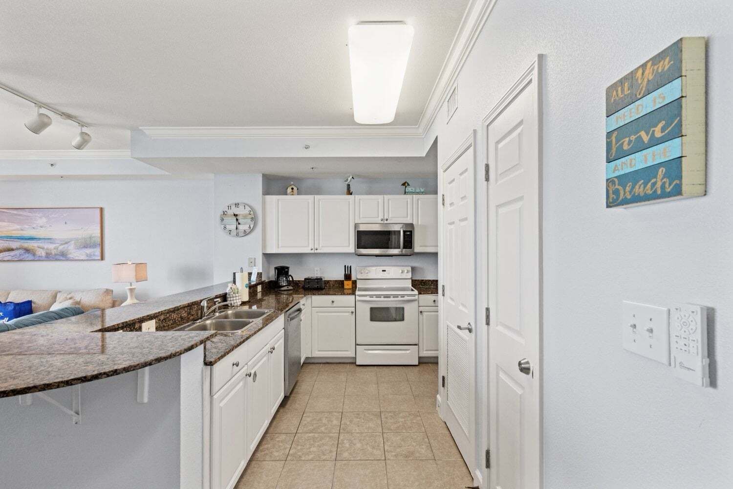 Eine kompakte Küche mit weißen Schränken, einer Mikrowelle, einem Backofen und einem Spülbecken.