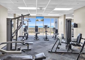 Ein Fitnessstudio mit Cardiogeräten, Gewichtstrainern und Blick auf den Strand.