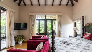 A bedroom with a large bed, a TV, a window with curtains, and a red sofa. - Staymaster Shangrila-4BR Private villa  (Marra)