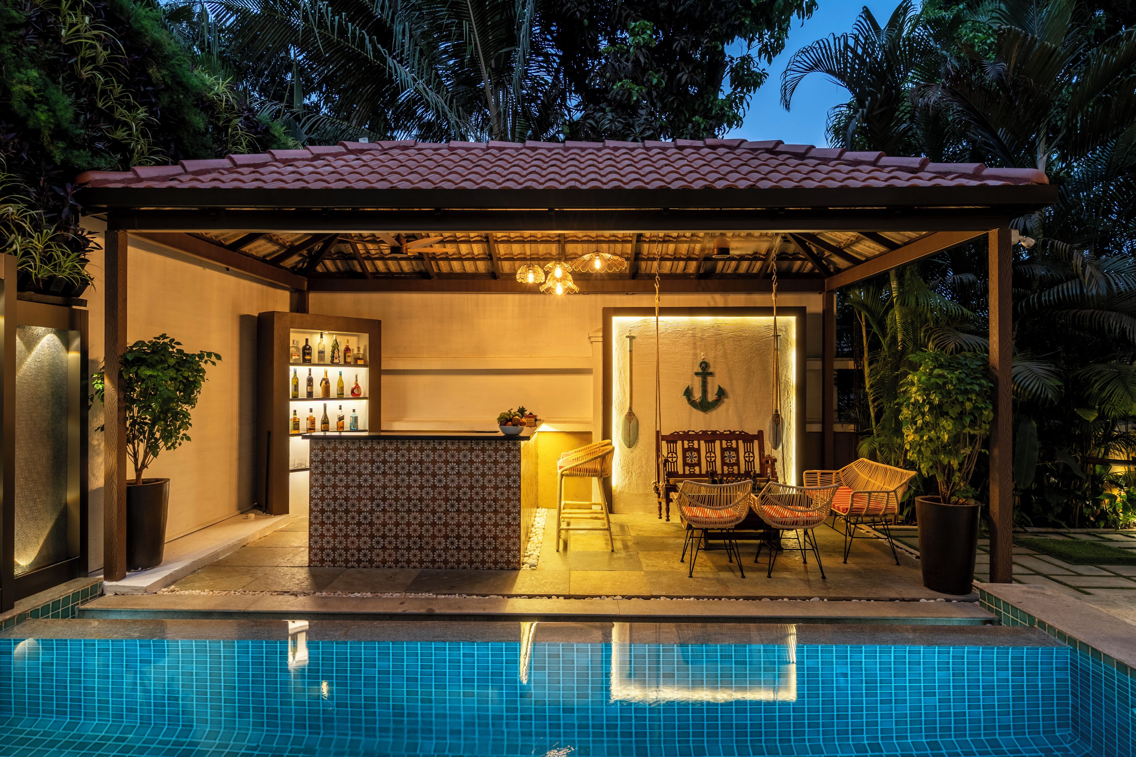 A poolside bar with a tiled roof, a seating area with wicker chairs, and a pool with blue tiles.