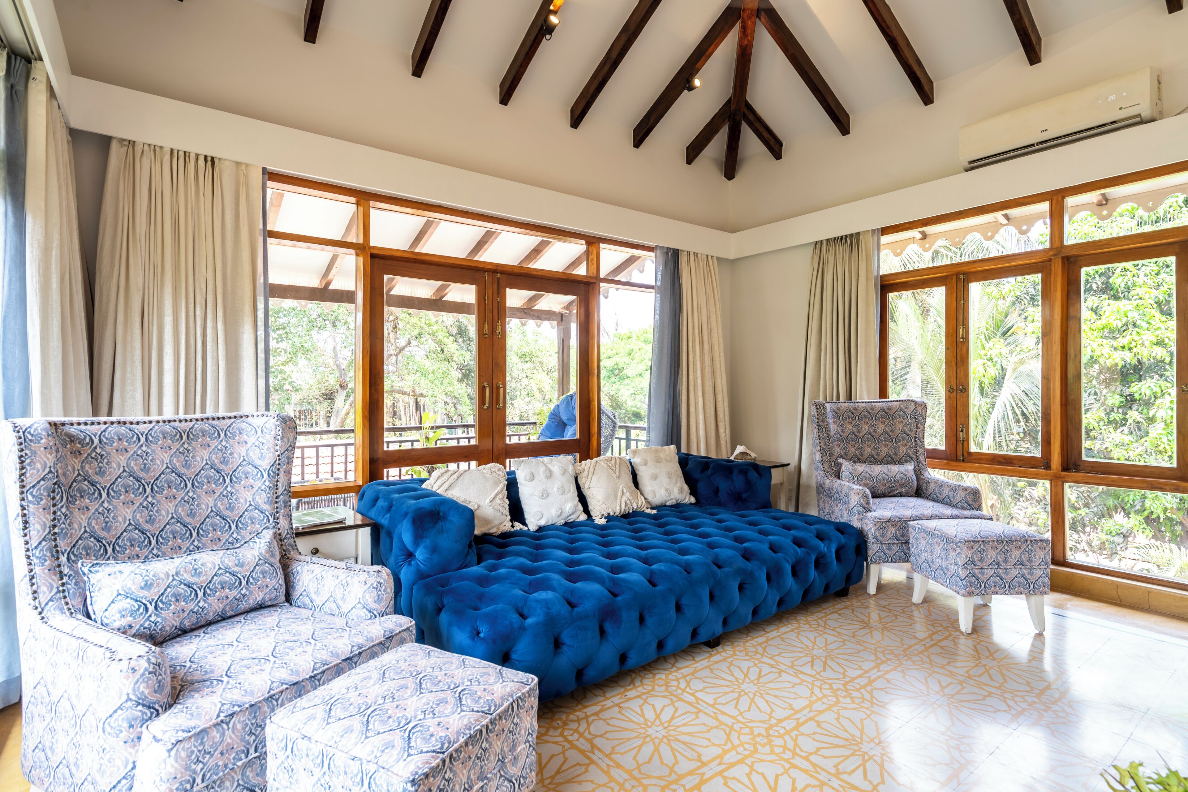 A spacious room with a large blue sofa, patterned armchairs, and a patterned rug.