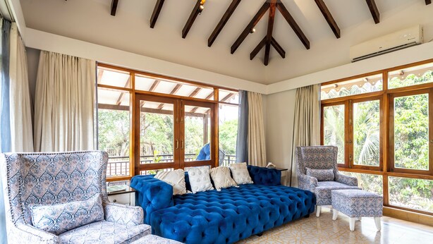 A spacious room with a large blue sofa, patterned armchairs, and a patterned rug. - Staymaster Shangrila-4BR Private villa  (Marra)