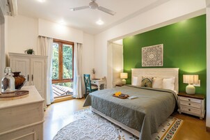Quarto com cama, mesas de cabeceira, escrivaninha, janela com cortinas e uma parede verde como detalhe.