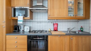 Ett kök med träskåp, en rostfri köksfläkt, en inbyggd ugn, en gasspis, en kaffebryggare och ett diskho.