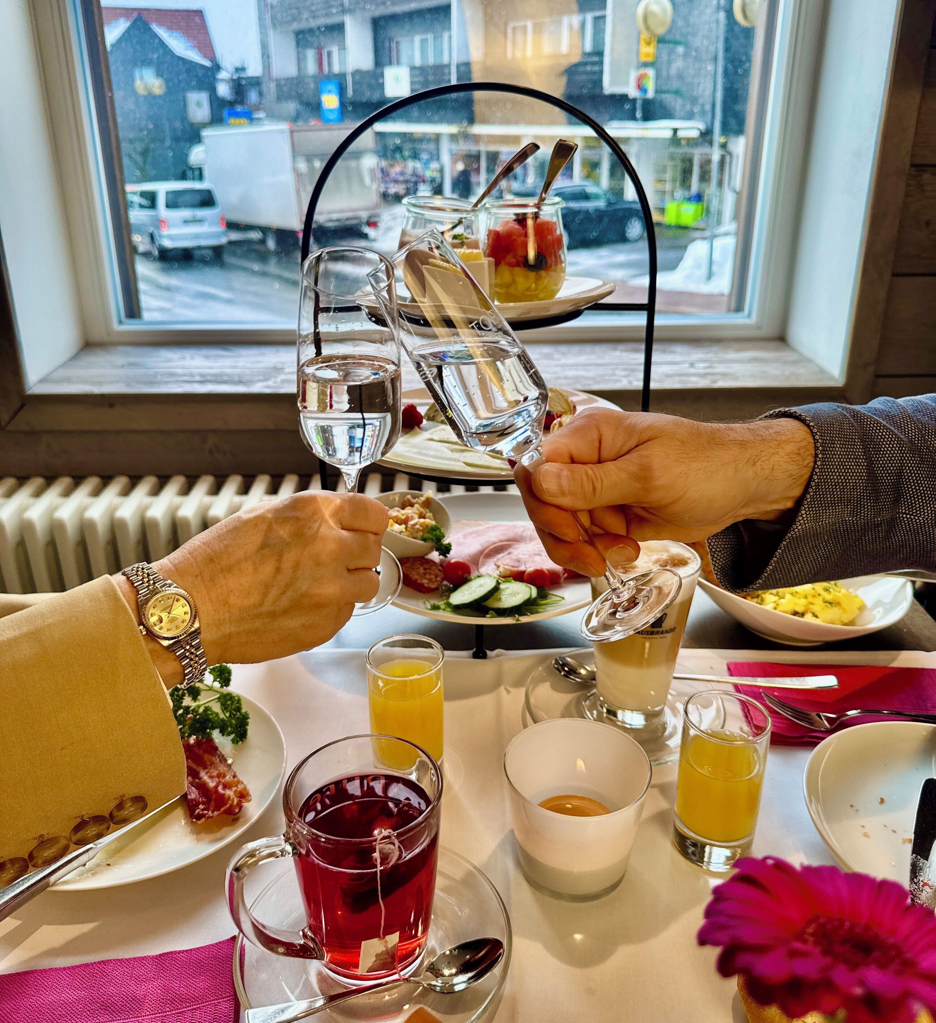 Une table à manger avec différents plats, des verres et une vue sur la fenêtre.