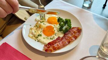 Une assiette avec des œufs, du bacon et du persil.