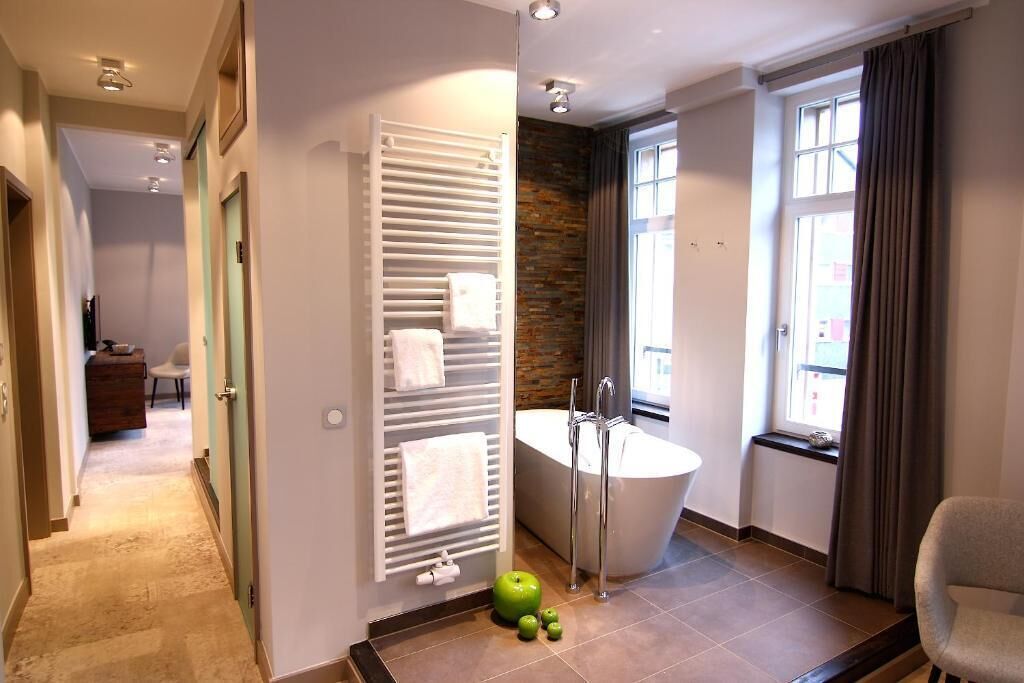 Ein Badezimmer mit Badewanne, Handtuchhalter und einem fenster mit Vorhängen.