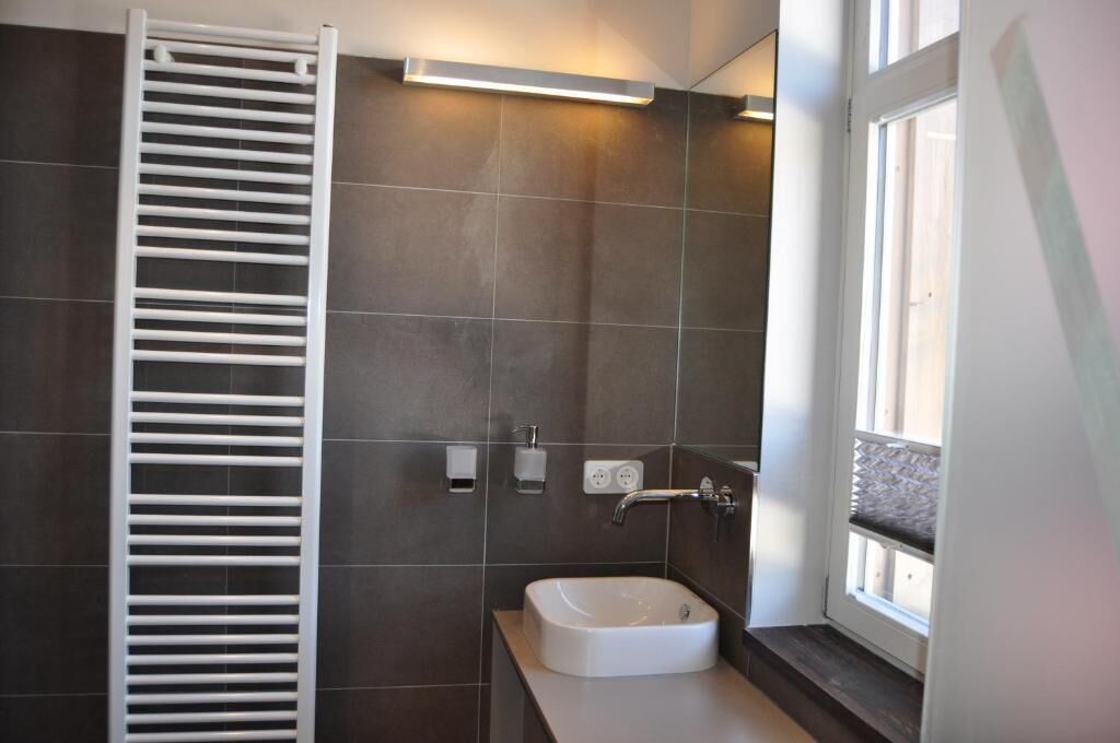 A bathroom with a white towel rack, a white sink, and a window.