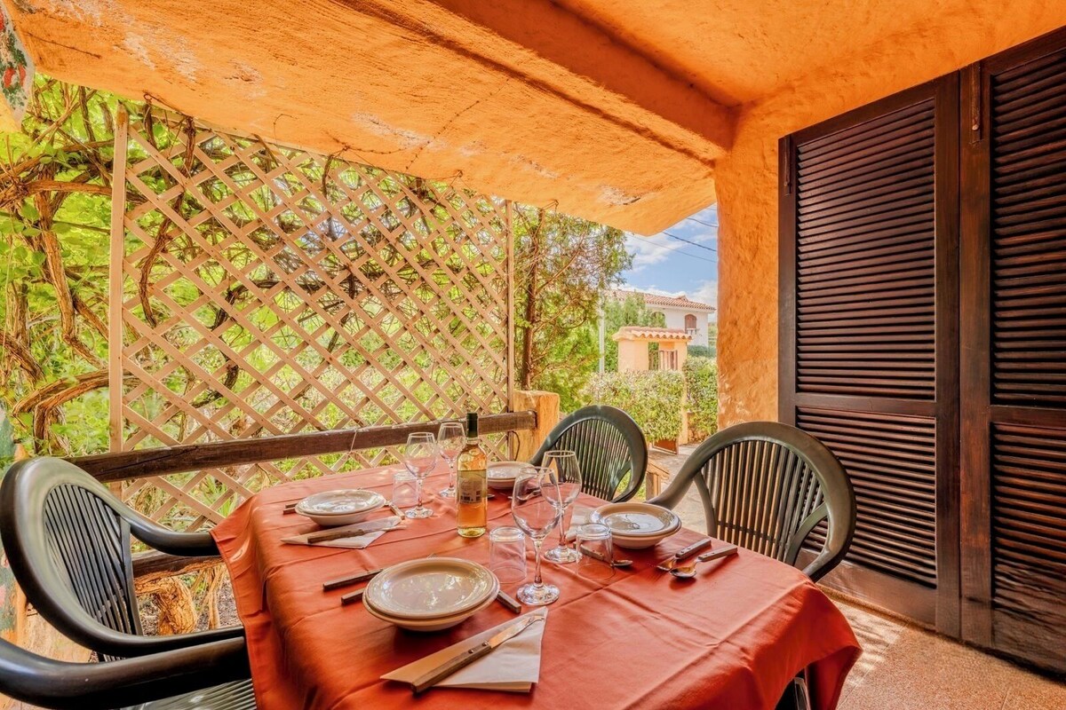 An outdoor dining area with a table set for two, surrounded by chairs, and a lattice backdrop.