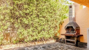 An outdoor area with a stone-tiled floor, a stone oven, and a dense green bush. - Margherite Apartments by Wonderful Italy (Porto Ottiolu)