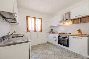 A compact kitchen with a gas stove, oven, and stainless steel sink. - Margherite Apartments by Wonderful Italy (Porto Ottiolu)