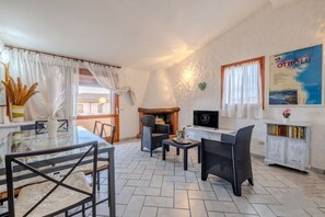 A cozy living area with a fireplace, comfortable seating, a dining table, and a TV. - Margherite Apartments by Wonderful Italy (Porto Ottiolu)