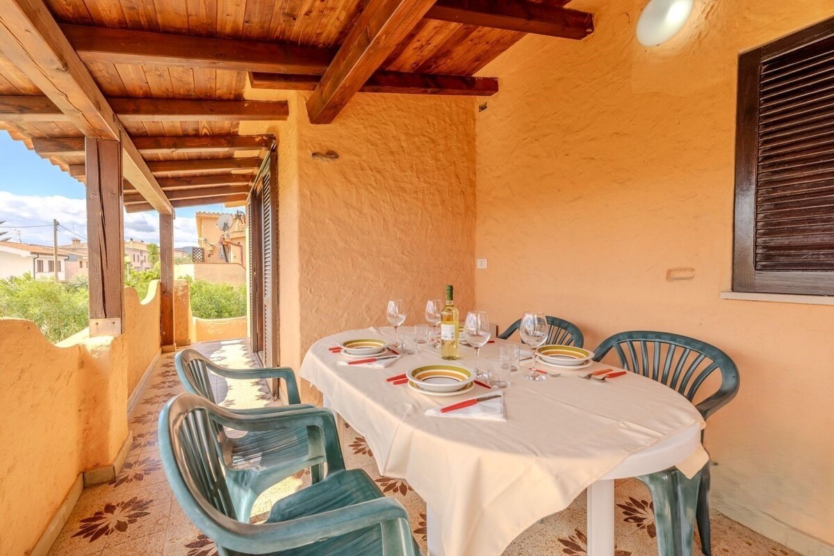 A dining area with a table set for two, wooden beams overhead, and a view of the surrounding area.