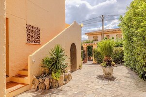 Un estrecho sendero de piedra que conduce a un edificio con una entrada decorativa y una escalera.