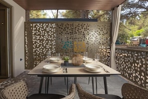 An outdoor dining area with a table set for four, surrounded by wicker chairs. - Maris Villas (Žaborić)