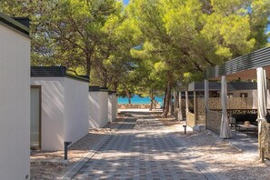 A pathway leading to a covered outdoor seating area with trees overhead.