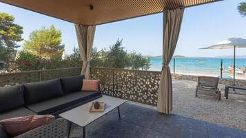 A covered outdoor seating area with a view of a beach and pool.