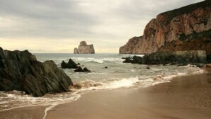Une plage côtière bordée de falaises rocheuses, offrant une vue dégagée sur la mer.