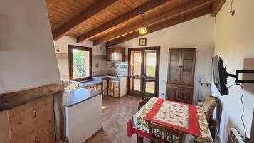 Una cucina compatta con soffitto in legno, un tavolo da pranzo con tovaglia e una televisione montata a parete.