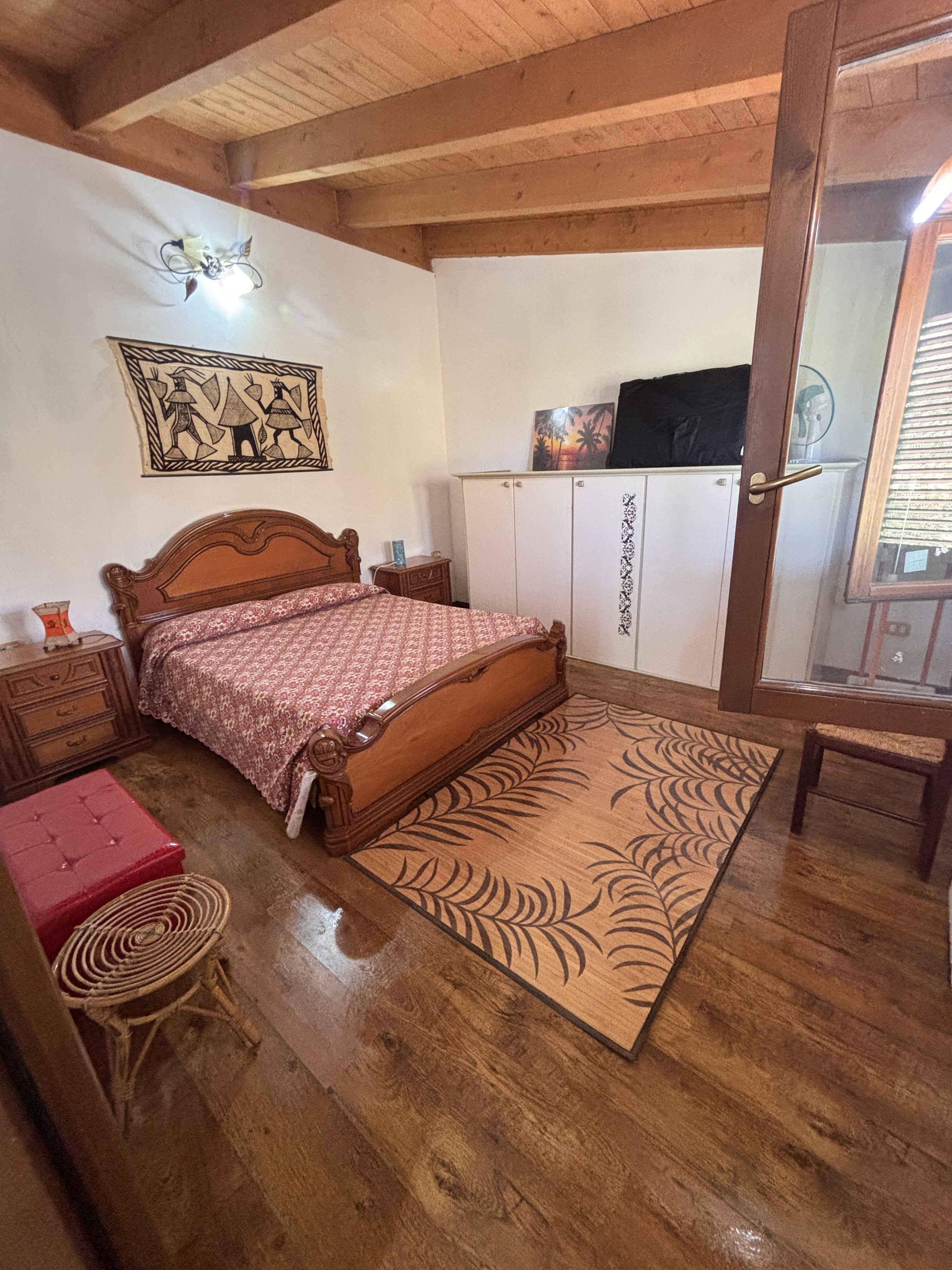 A bedroom with a wooden bed, a wardrobe, a small table, and a bench.
