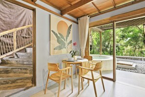 A room with a dining table and chairs, a painting, and a view of greenery outside. - Sakara Bali Villa by Kozystay - Ubud (Kabupaten Gianyar)