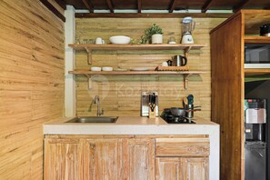 A kitchen with wooden cabinets, a sink, a stove, and various kitchen utensils. - Sakara Bali Villa by Kozystay - Ubud (Kabupaten Gianyar)
