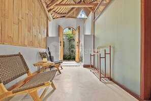 A hallway with a bamboo ceiling, a wooden bench, a small table with a plant, and a doorway leading to a garden. - Sakara Bali Villa by Kozystay - Ubud (Kabupaten Gianyar)