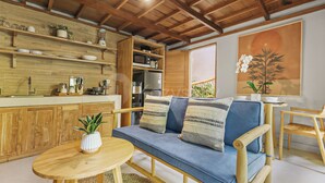 A cozy living area with a sofa, a small round table, and a kitchen area with wooden cabinets and a microwave. - Sakara Bali Villa by Kozystay - Ubud (Kabupaten Gianyar)