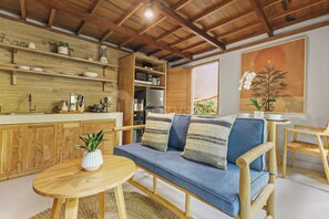 A cozy living area with a sofa, a small round table, and a kitchen area with wooden cabinets and a microwave. - Sakara Bali Villa by Kozystay - Ubud (Kabupaten Gianyar)