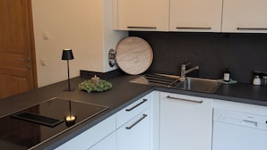 Eine moderne Küche mit weißen Schränken, einer schwarzen Arbeitsplatte und einem eingebauten Geschirrspüler.