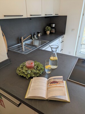 Eine moderne Küche mit schwarzem Arbeitsplatz, einer Edelstahl-Spüle und einem Blumentopf.