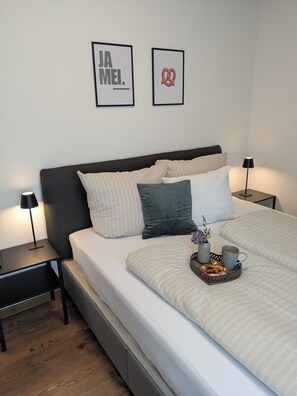 A neatly made bed with a tray of breakfast items, two bedside lamps, and two framed pictures on the wall. - 100-square-meter vacation rental with 3 separate bedrooms (Ruhpolding)