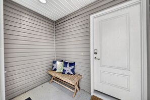 A corner of a room with a bench, a door, and a ceiling with horizontal siding.