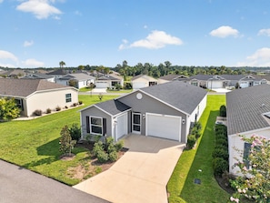 A residential area with single-story houses, a clear sky, and well-maintained lawns.