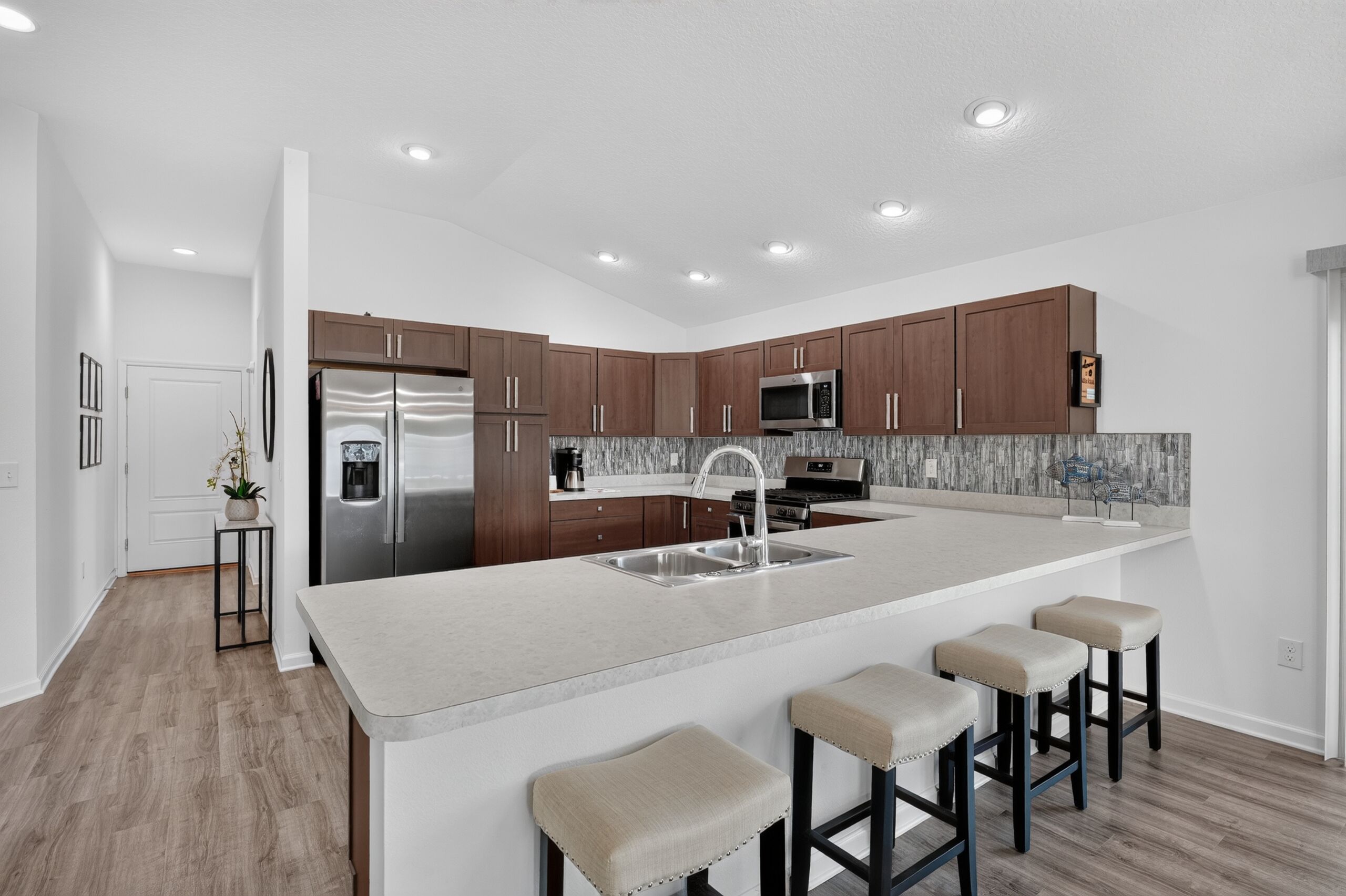Une cuisine moderne dotée d’appareils électroménagers en acier inoxydable, de meubles de rangement en bois et d’un grand îlot central avec des tabourets de bar.