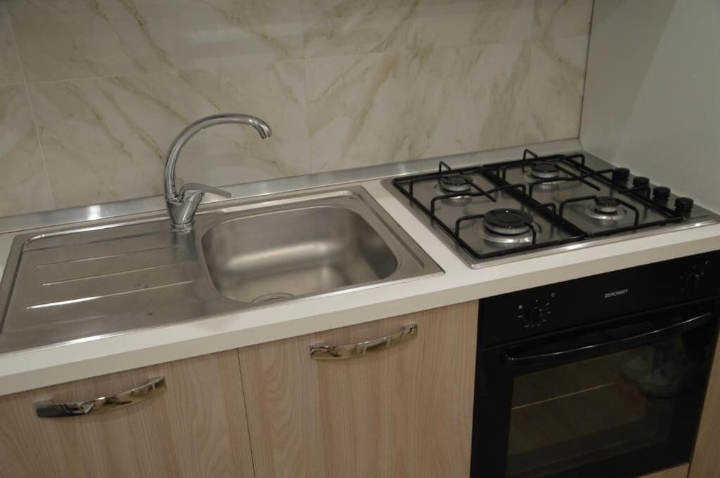 A kitchen with a stainless steel sink, a gas stove, and a black oven.