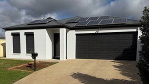 Ett modernt hus i två våningar med ett garage, en överbyggd uppfart och solpaneler på taket.