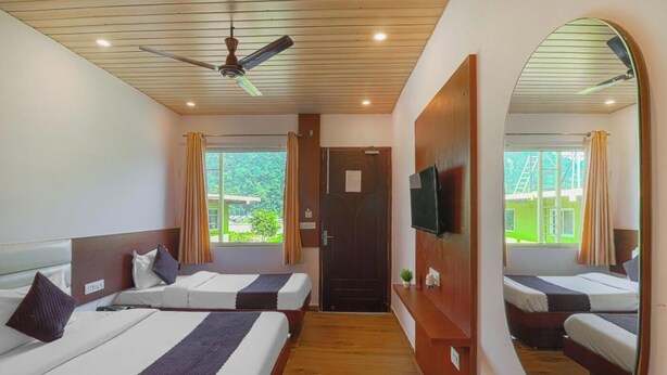 A hotel room with two beds, a ceiling fan, a TV, and a large mirror. - PrideInn Luxury Resort (Simal Khet)