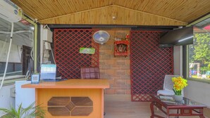 A reception area with a wooden desk, a computer, a fan, and a red lattice partition. - PrideInn Luxury Resort (Simal Khet)