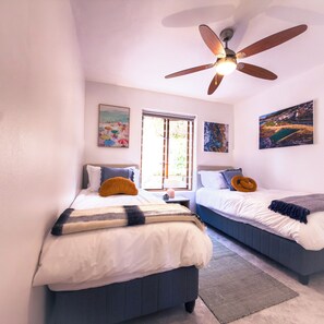 Ein Schlafzimmer mit zwei Betten, einem Deckenventilator und Kunstwerken an den Wänden.