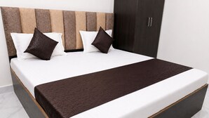 A bed with a wooden headboard, white bedding, and a brown throw blanket. - Spacious 5-bedroom building in marvelous Mathura with AC (mathura)
