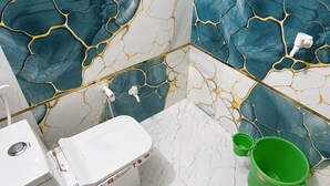 A bathroom with a white toilet, a green bucket, and a sink with a faucet. - Spacious 5-bedroom building in marvelous Mathura with AC (mathura)