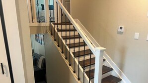 Una escalera con barandilla blanca y balaustres negros, que conduce a un piso superior.